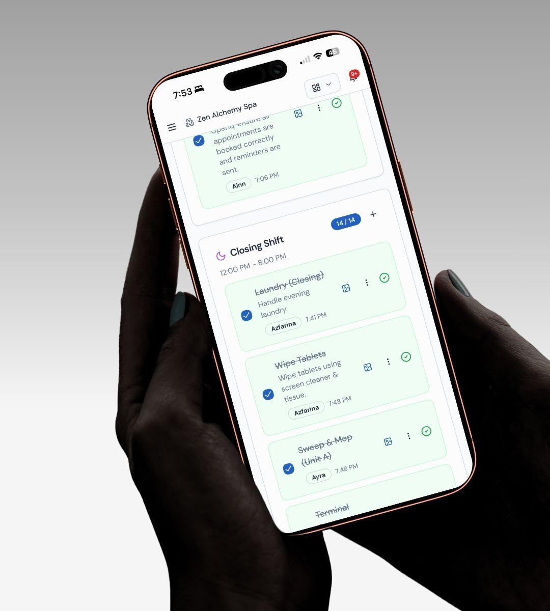 A phone held in both hands showing Operiq’s closing shift checklist, with laundry, wiping tablets and sweeping ticked off against the member of staff who did each one and the time they finished.